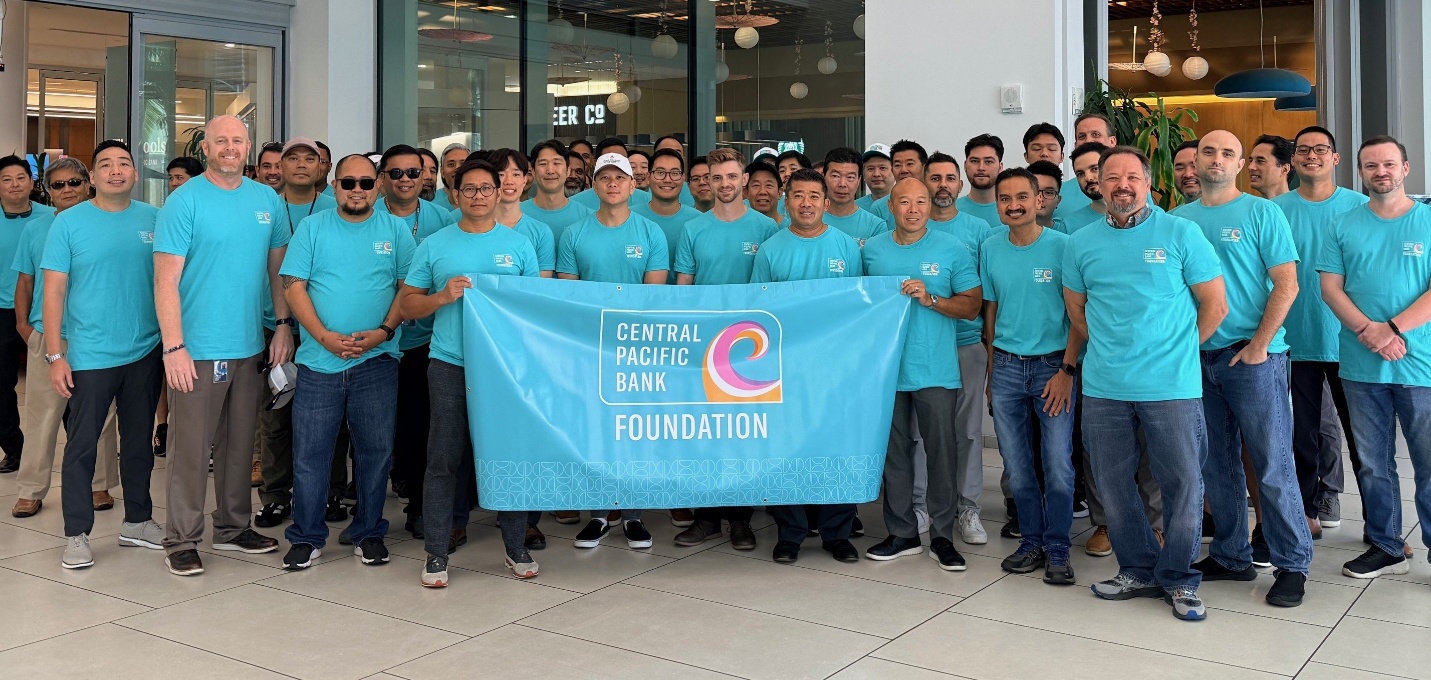 A group of Central Pacific Bank Foundation volunteers poses with a foundation banner during a domestic violence awareness initiative.