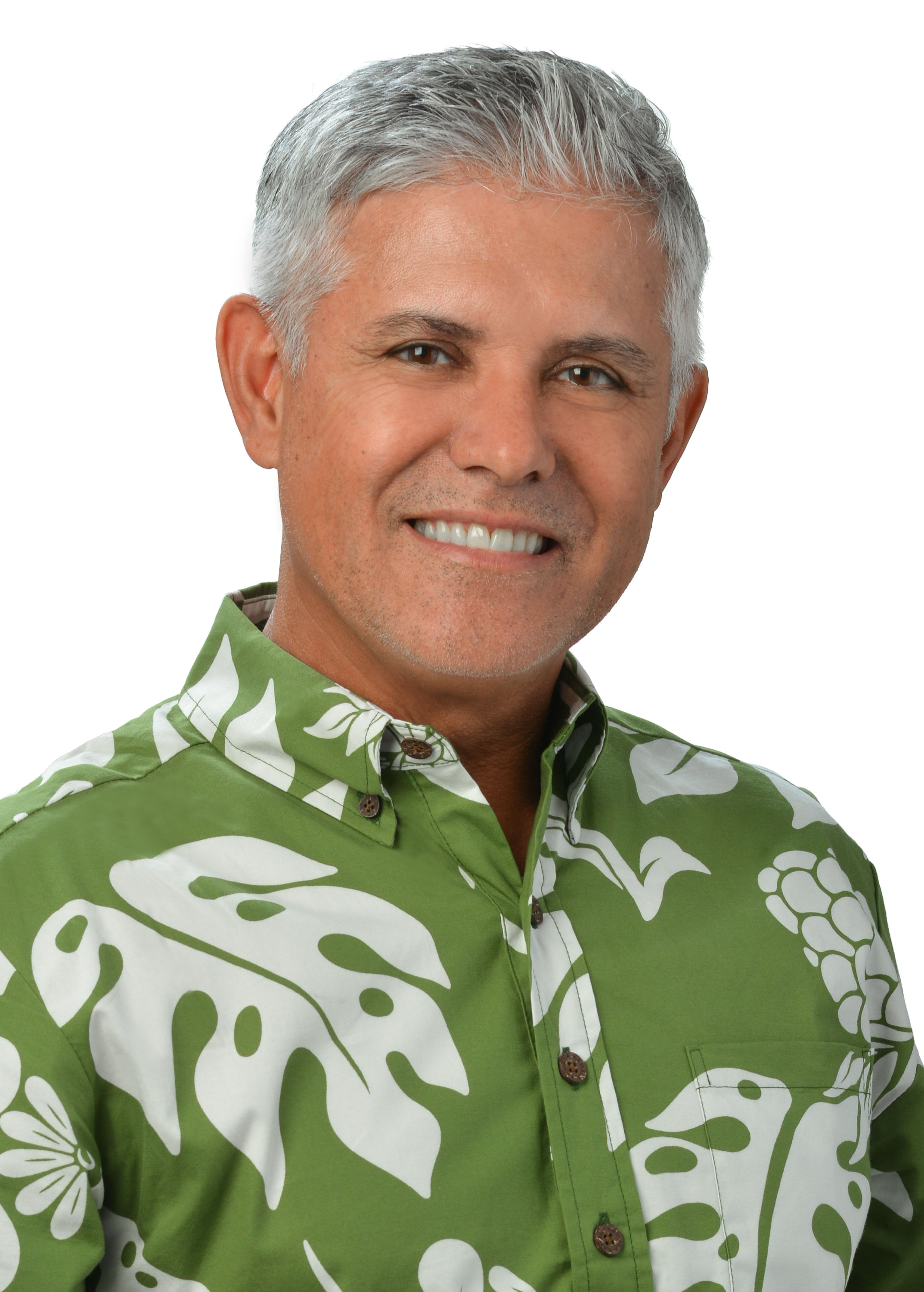 A professional headshot of a person with short gray hair wearing a green aloha shirt with a large white tropical leaf pattern, photographed against a light gray background.