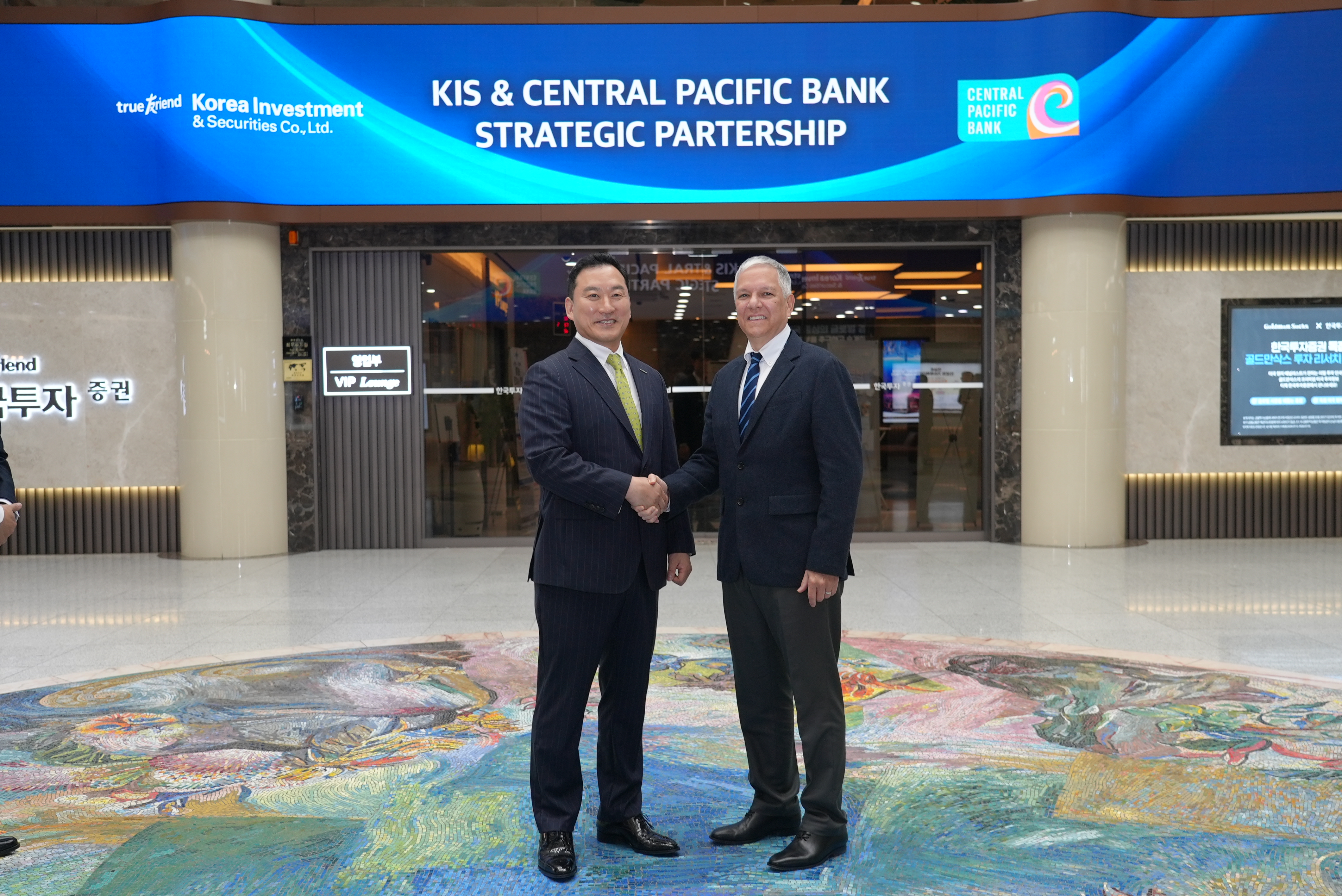 Central Pacific Bank and Korea Investment & Securities leaders pose during a partnership event, standing beneath a display highlighting the strategic collaboration.