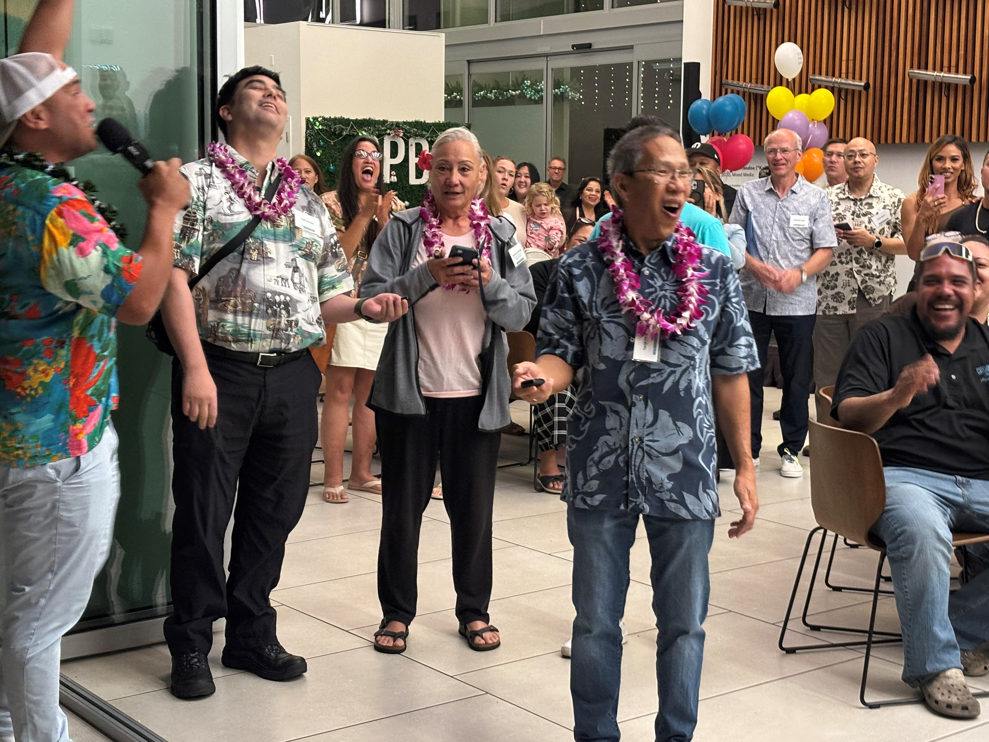 Darrly Pang reacts as he is announced as the winner during a prize giveaway event, while attendees gather and celebrate in the background.